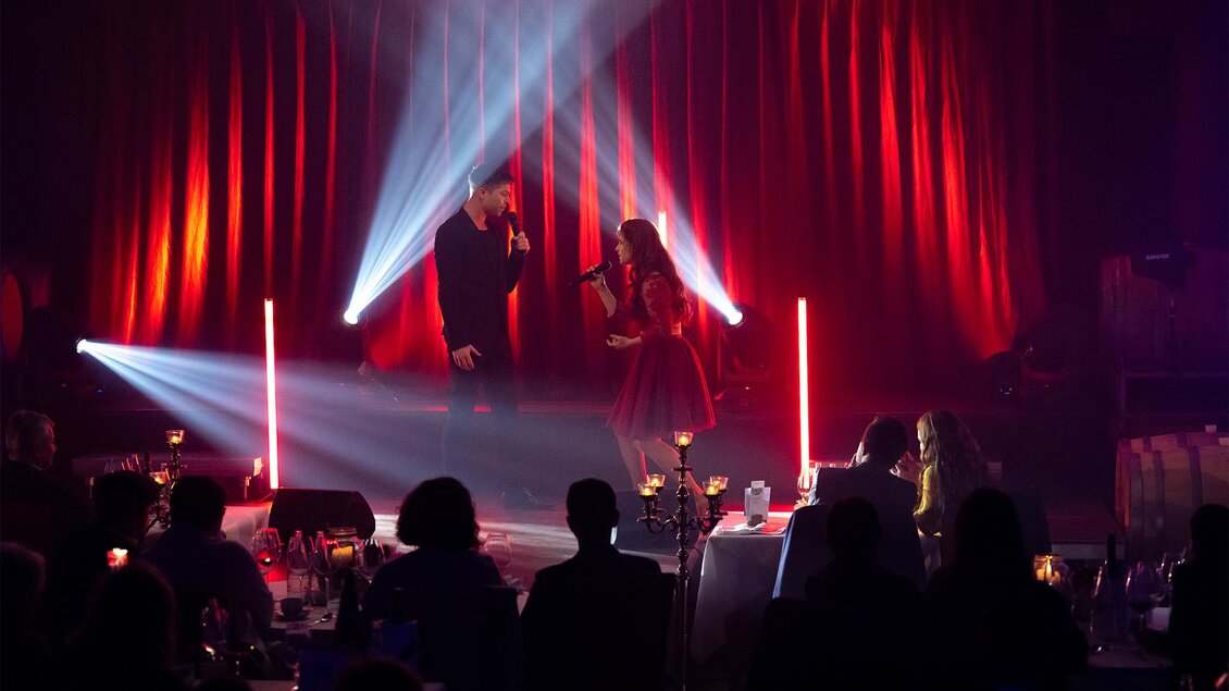 Ein Live-Auftritt mit zwei Sängern auf einer Bühne. Die Atmosphäre ist lebhaft mit bunten Lichtern und Zuschauern, die genießen. | © Anja Wendzel