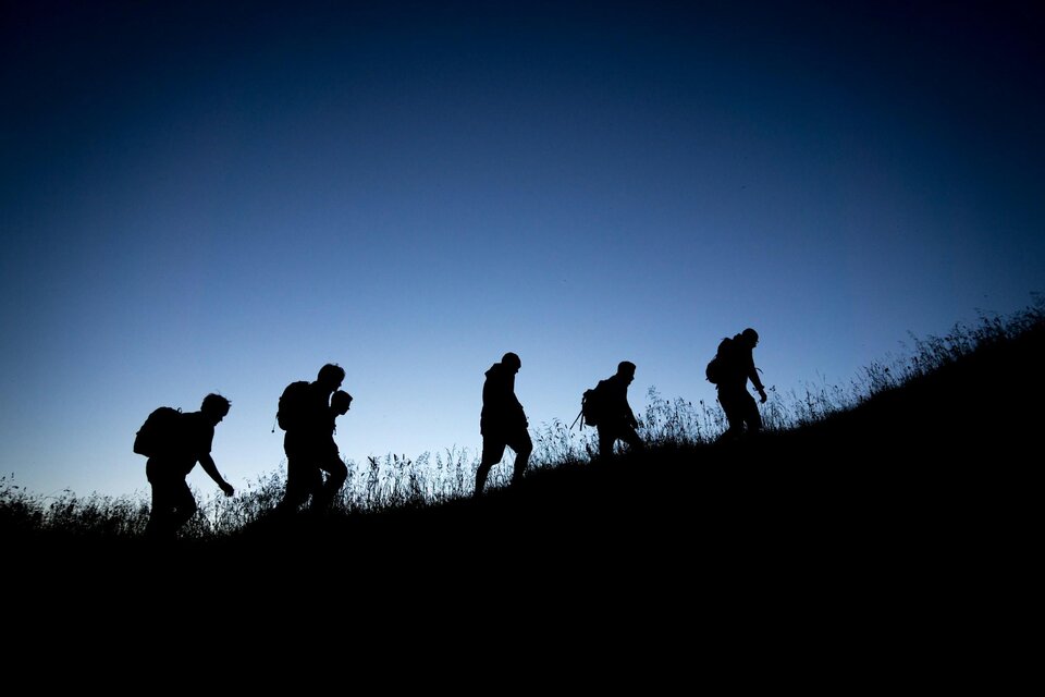 Silhouetten von fünf Wanderern mit Rucksäcken beim Aufstieg auf den Schöckl vor dunkelblauem Abendhimmel. | © Tobias Mrzyk-Unsplash