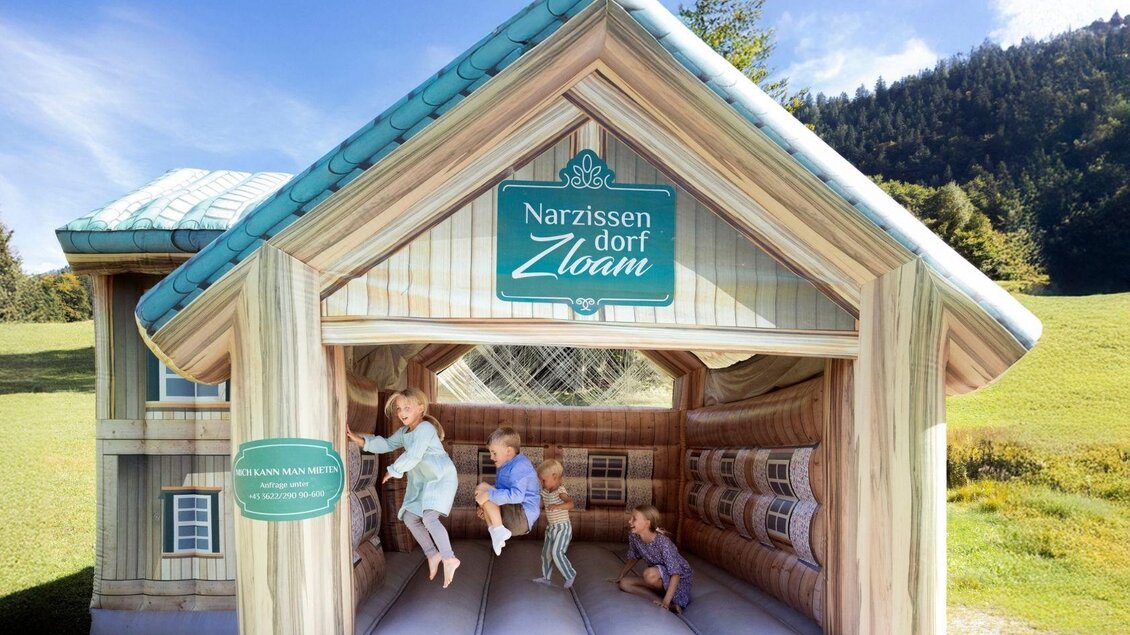 Ein buntes Spielhaus im Freien mit einem einladenden Eingang. Kinder spielen fröhlich darin und genießen die frische Luft. | © www.zloam.at