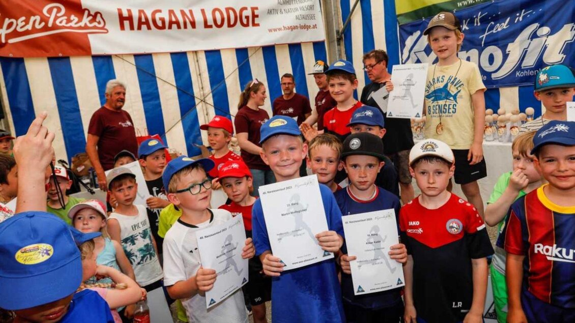 Eine Gruppe von Kindern steht stolz mit Urkunden in der Hand. Im Hintergrund sind bunte Banner und weitere Kinder zu sehen. | © Kainzinger Erich