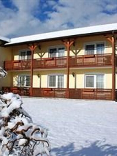 Ein Gebäude im Winter, umgeben von Schnee. Es hat mehrere Balkone und einen klaren Himmel im Hintergrund. | © Teuschler-Mogg