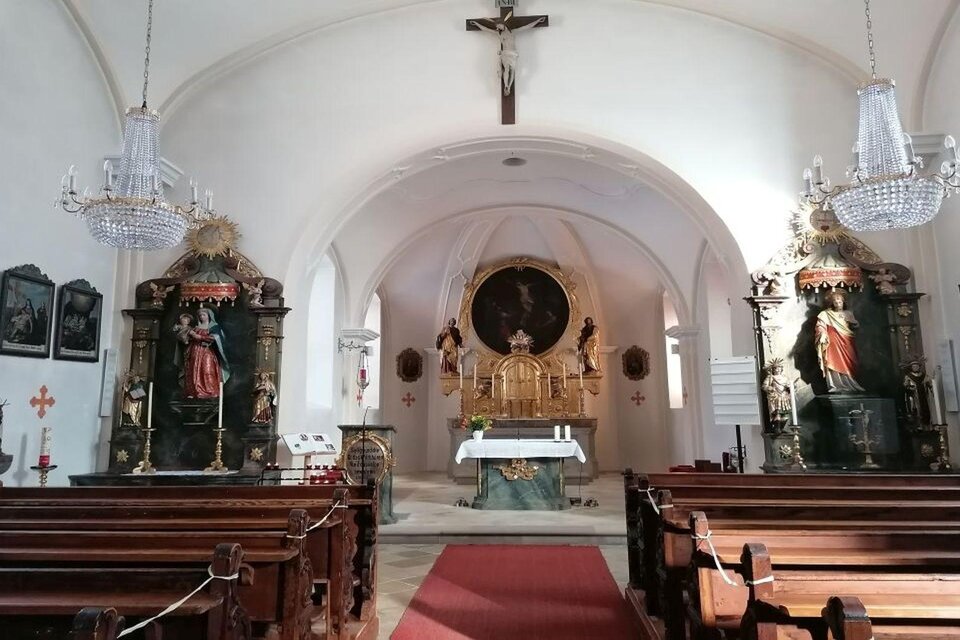 Eine ruhige Kirche mit Holzbankreihen und einem Altar im Mittelpunkt. An den Wänden stehen religiöse Statuen und Kunstwerke. | © TVB Ausseerland Salzkammergut_Kolb