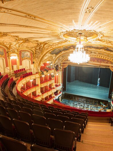 A magnificent theater with opulent decoration and red plush. The rows of seats offer a view of the empty stage. | © (c) Graz Tourismus - Harry Schiffe