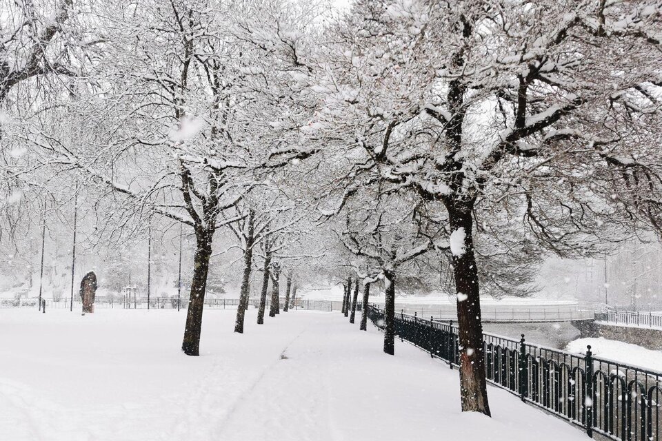 Winterliche Aufnahme von Bad Aussee im Kurpark mit Blick auf die Mercedesbrücke. Die Landschaft ist tief verschneit, während dichter Schneefall für eine stimmungsvolle, winterliche Atmosphäre sorgt. | © Theresa Schwaiger