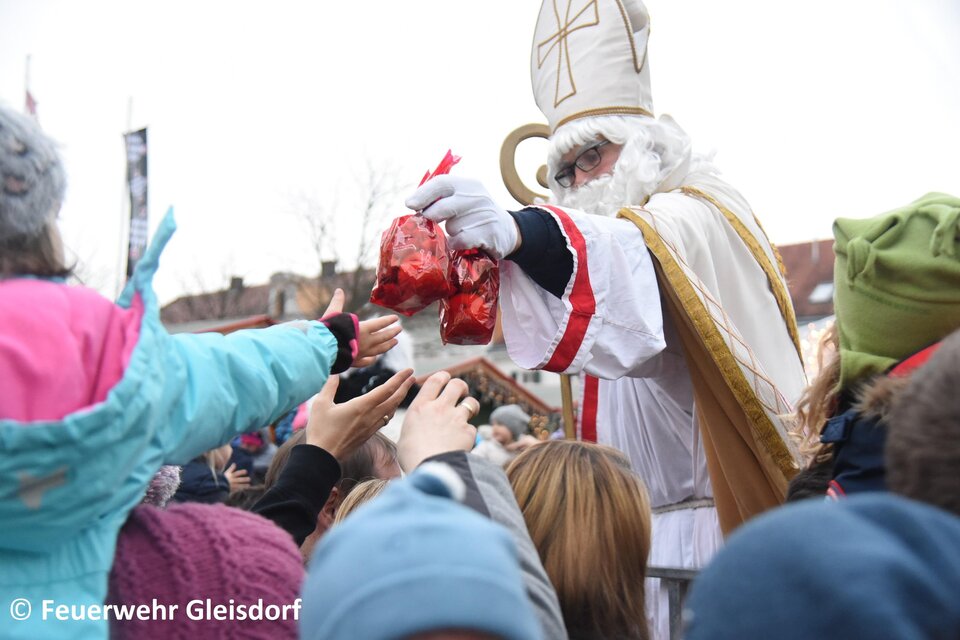 Der Nikolaus verteilt Geschenke an eine wartende Menschenmenge. Viele Kinder strecken ihre Hände aus, um Süßigkeiten zu erhalten. | © Tourismusverband Oststeiermark