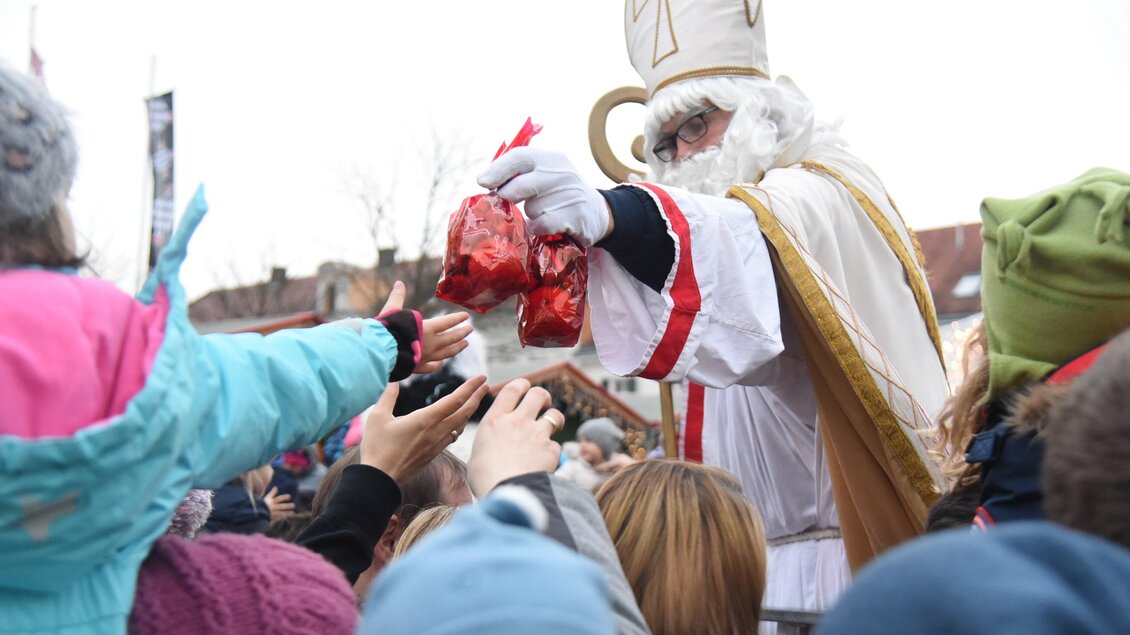 Der Nikolaus verteilt Geschenke an eine wartende Menschenmenge. Viele Kinder strecken ihre Hände aus, um Süßigkeiten zu erhalten. | © Tourismusverband Oststeiermark