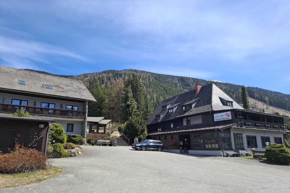 Ein malerisches Hotelgebäude umgeben von Bäumen und Bergen. Der Parkplatz ist weitläufig und bietet Platz für mehrere Fahrzeuge. | © Draxlerhaus