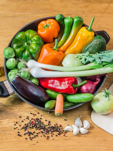 A variety of fresh vegetables is arranged in a pan, including bell peppers, zucchini, and cauliflower. Next to it are two bottles of olive oil and various spices. | © NP Gesäuse