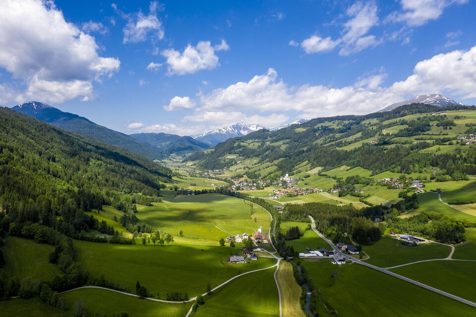 Eine malerische Landschaft mit grünen Wiesen und Bergen im Hintergrund. Der Himmel ist klar und blau, während die Wolken sanft ziehen. | © Tv Murau