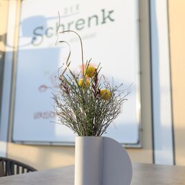 Eine dekorative Blumenvase mit getrockneten Blumen steht auf einem Tisch. Im Hintergrund ist ein Schild mit dem Namen "Schrenk" zu sehen. | © Tourismusverband Oststeiermark