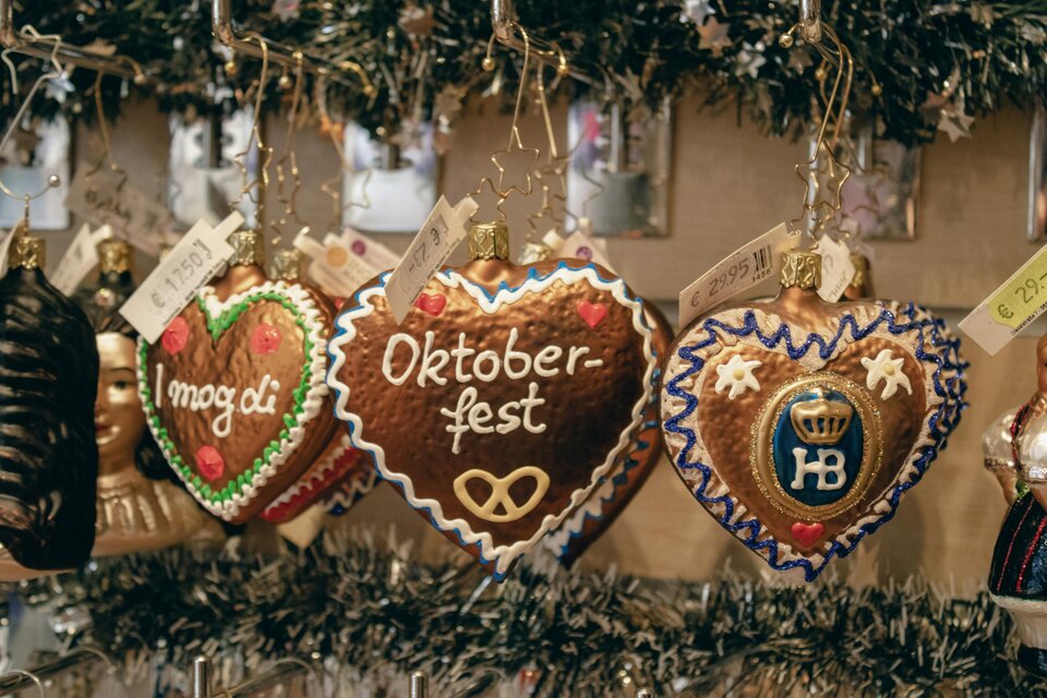 Bunte Lebkuchenherzen mit verschiedenen Beschriftungen, darunter "Oktoberfest". Sie hängen dekorativ an einem Stand. | © marlene-haiberger-unsplash
