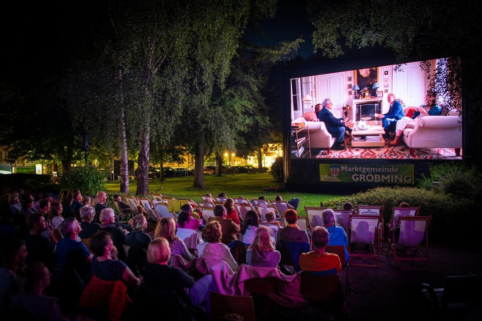 Eine Nachtfilmvorführung im Freien mit vielen Zuschauern. Auf einer großen Leinwand ist eine Szene aus einem Film zu sehen. | © Christoph Huber