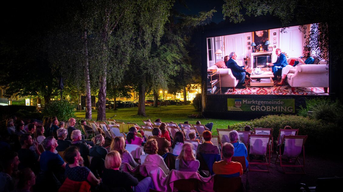 Eine Nachtfilmvorführung im Freien mit vielen Zuschauern. Auf einer großen Leinwand ist eine Szene aus einem Film zu sehen. | © Christoph Huber