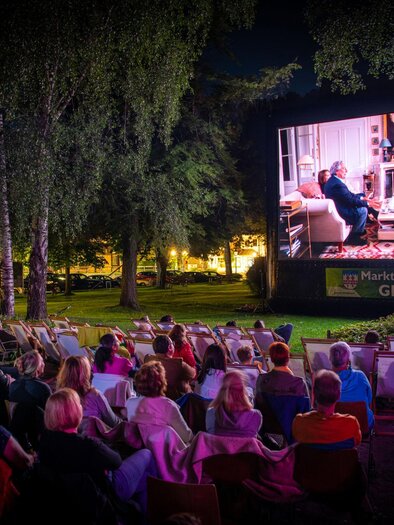Eine Nachtfilmvorführung im Freien mit vielen Zuschauern. Auf einer großen Leinwand ist eine Szene aus einem Film zu sehen. | © Christoph Huber
