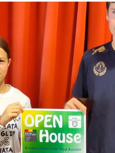 Zwei Jugendliche halten ein Plakat für einen Tag der offenen Tür an der Bundeshausschule Bad Aussee. Das Plakat enthält Informationen zur Veranstaltung und zeigt die Schule. | © Bundesschulzentrum Bad Aussee