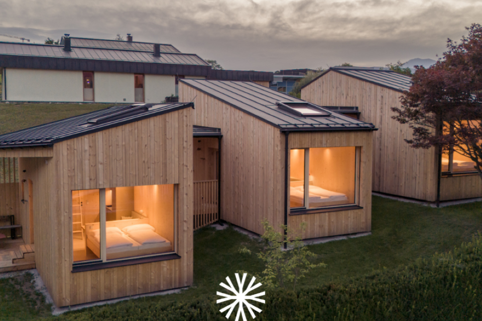 Moderne, gemütlich beleuchtete Holzhäuser in ruhiger Abendstimmung. | © biYou - das Ecoquartier in den Bergen