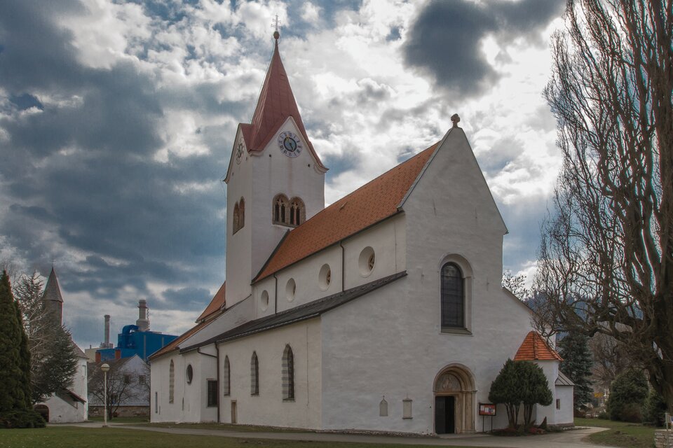 Eine weiße Kirche mit rotem Dach und einem hohen Turm. Der Himmel ist bewölkt und es gibt viel Grün in der Umgebung. | © Markus Beren