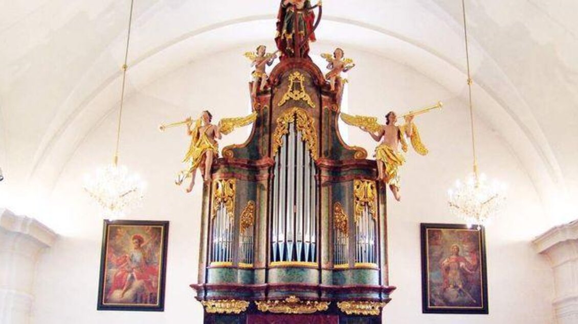 Eine prunkvolle Kirchenorgel mit goldenen Engeln und kunstvollen Verzierungen. Im Hintergrund sind zwei Bilder an der Wand zu sehen. | © Oststeiermark Tourismus