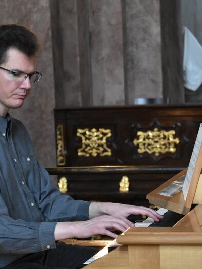 A man is playing the piano in an elegant room. Ornately decorated furniture can be seen in the background. | © TVB Murau