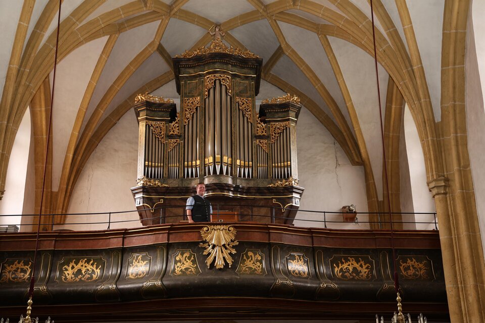 Eine wunderschöne Kirche mit einem markanten Turm und roten Dächern. Umgeben von grünen Wiesen und kleinen Häusern. | © Pfarre Krieglach