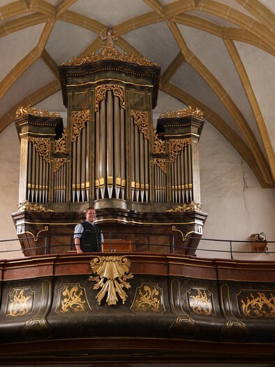 Eine wunderschöne Kirche mit einem markanten Turm und roten Dächern. Umgeben von grünen Wiesen und kleinen Häusern. | © Pfarre Krieglach