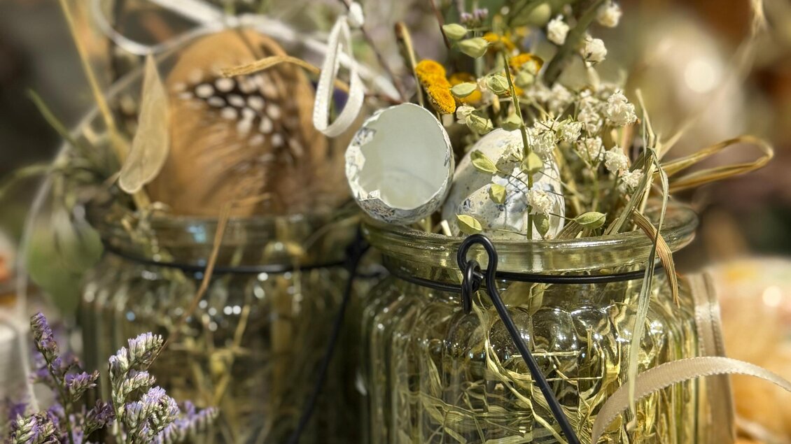 Zwei Gläser mit Trockenblumen und dekorativen Elementen stehen zusammen. Die Gläser sind mit Bändern verziert und umgeben von weiteren natürlichen Materialien. | © Schloss Kornberg