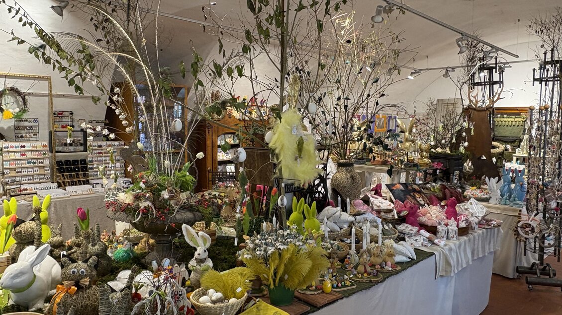 Ein schön dekorierter Verkaufsraum mit vielen fröhlichen Osterdekorationen. Bunte Figuren, Blumen und Zweige sind auf den Tischen angeordnet. | © Thermen- & Vulkanland/Christian Thomaser