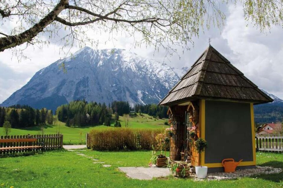 Ein heller Kirchenraum mit einem goldenen Altar und bunten Fensterbildern. Es gibt eine schlicht gedeckte Tafel und Bänke für die Gemeinde. | © Gernot Brennsteiner