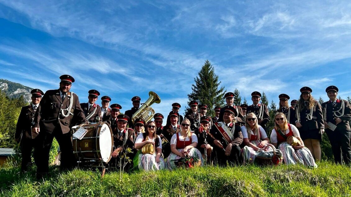 <p>Die Feuerwehrmusikkapelle Lupitsch gekleidet in ihren Musikuniformen stehen auf einer Wiese. Im Hintergrund ist ein blauer Himmel mit einigen Wolken zu sehen.</p> | © Carolina Daxner