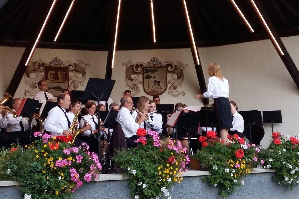 Eine Musikkapelle spielt unter einer überdachten Bühne. Bunte Blumenstöcke schmücken den Bereich. | © Petra Kirchschlager