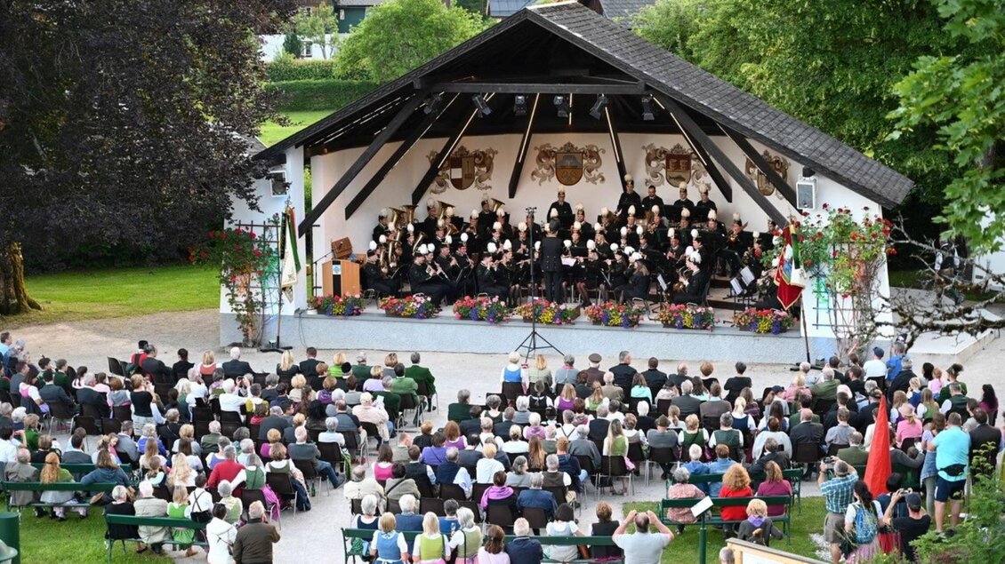 Ein großes Publikum sitzt in einem Freiluftveranstaltungsraum. Auf der Bühne treten mehrere Sänger und Musiker auf, umgeben von einer schönen grünen Landschaft. | © Florian Seiberl_Redaktion Alpenpost