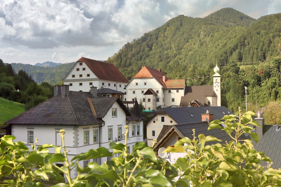 Eine malerische Landschaft mit traditionellen Häusern und sanften Hügeln. Im Hintergrund sind Wälder und Berge zu sehen. | © WEGES