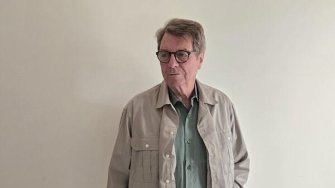 Ein älterer Mann steht vor einer neutralen Wand. Er trägt eine bequeme Jacke und eine Brille. | © Christiana Pock-Rosei