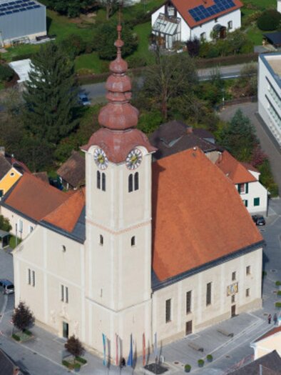A church with a distinctive bell tower and a red roof. Surrounded by residential houses and trees. | © Marktgemeinde Eibiswald
