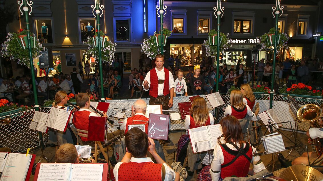 Eine Musikgruppe spielt auf einer Bühne vor einer Menschenmenge. Der Dirigent leitet das Ensemble energetisch. | © Harald Steiner