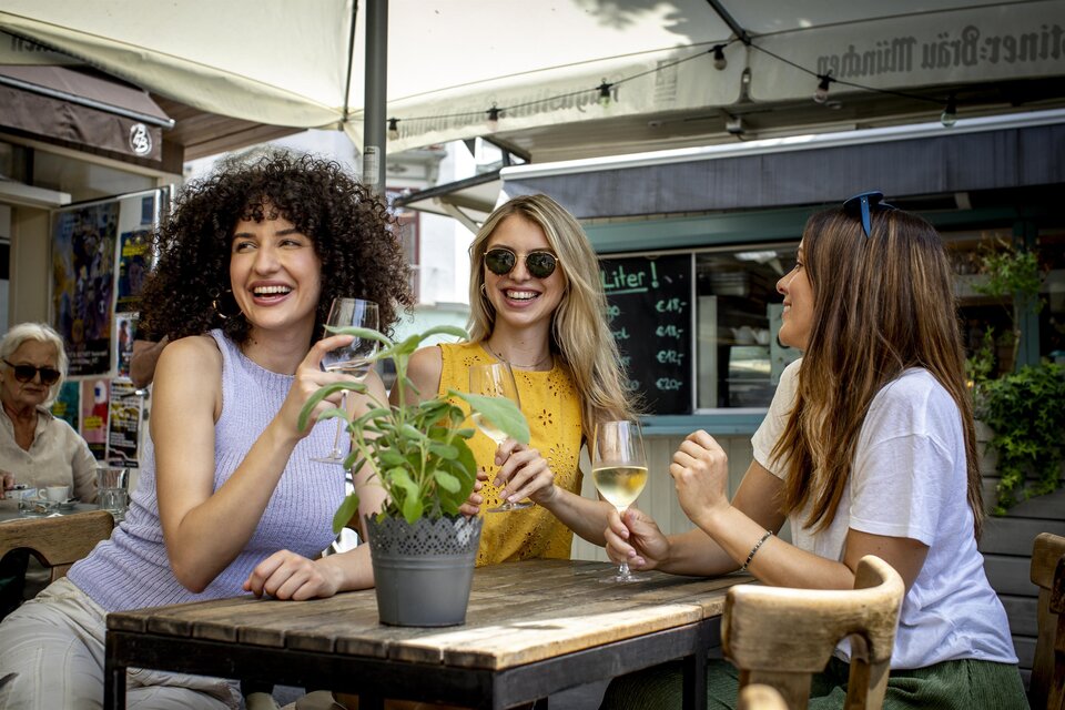 Drei Frauen sitzen an einem Tisch in einem Café und genießen Getränke. Es herrscht eine fröhliche Stimmung und es gibt ein grünes Pflänzchen auf dem Tisch. | © (c) Graz Tourismus - Tom Lamm