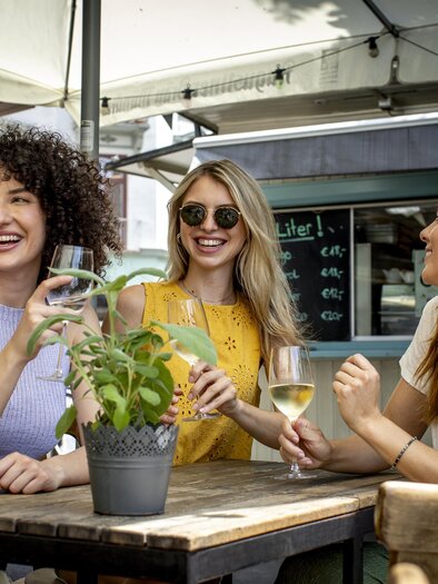 Drei Frauen sitzen an einem Tisch in einem Café und genießen Getränke. Es herrscht eine fröhliche Stimmung und es gibt ein grünes Pflänzchen auf dem Tisch. | © (c) Graz Tourismus - Tom Lamm