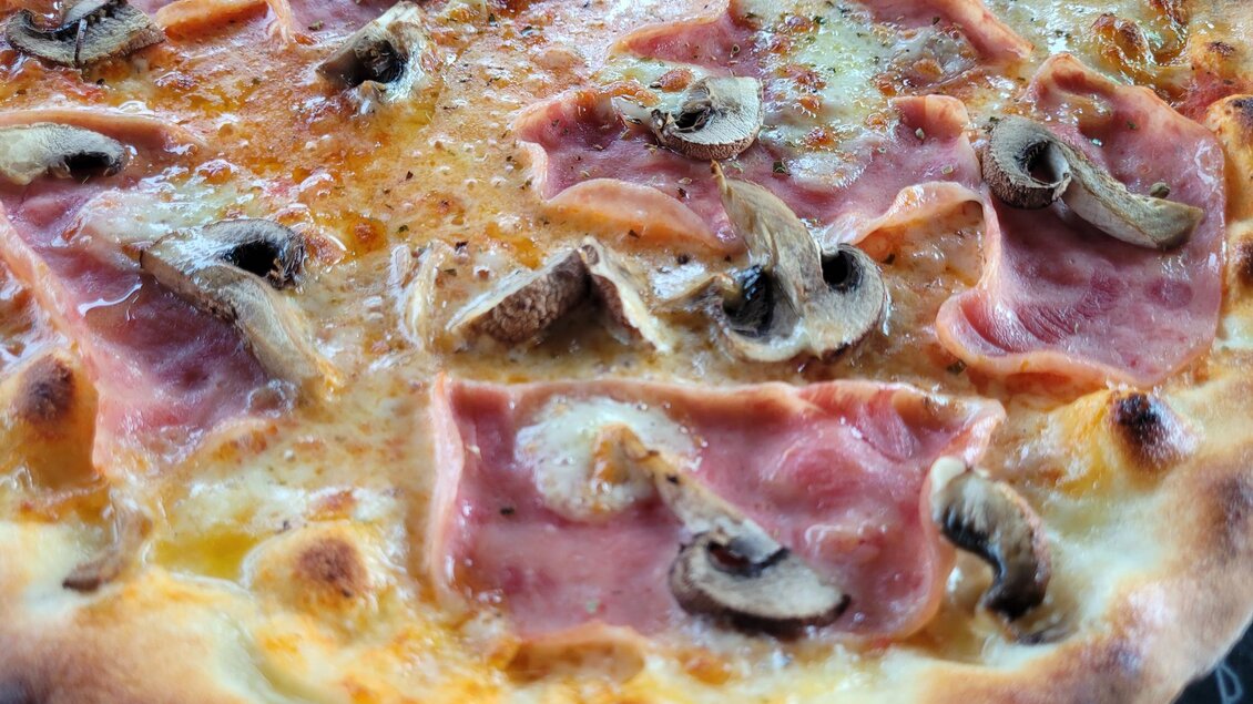Eine leckere Pizza mit Schinken und Champignons. Der Teig ist goldbraun und knusprig. | © TV Südsteiermark - Irene Löschnig