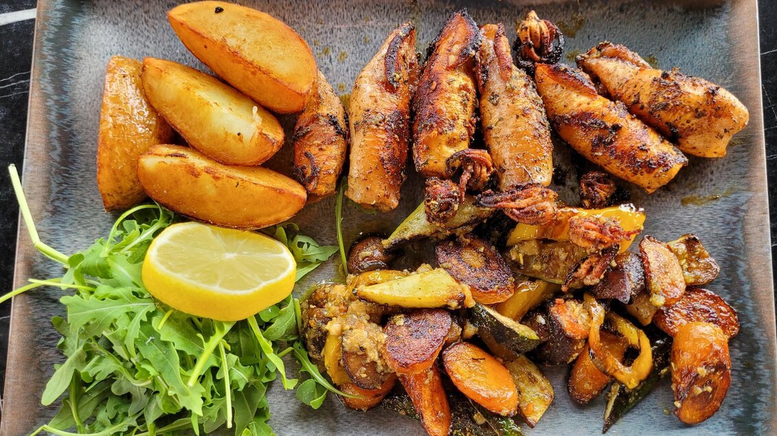 Ein Teller mit gegrilltem Geflügel, buntem Gemüse und knusprigen Kartoffelspalten. Ein frischer Salat und eine Zitronenscheibe runden das Gericht ab. | © TV Südsteiermark - Irene Löschnig