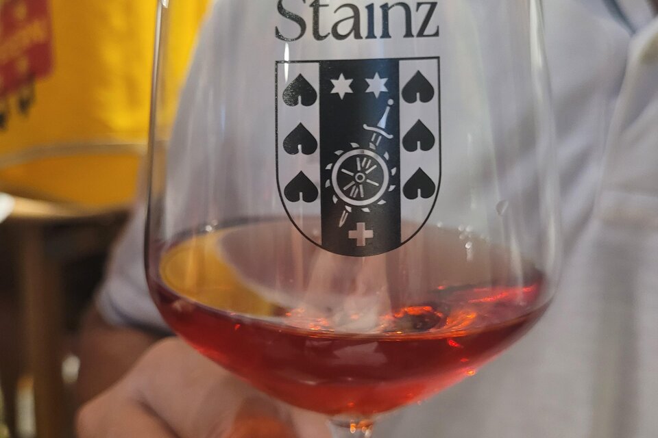 Ein Weinglas mit dem Wappen von Stainz. Der Inhalt ist ein rötlicher Wein. | © TV Südsteiermark - Irene Löschnig