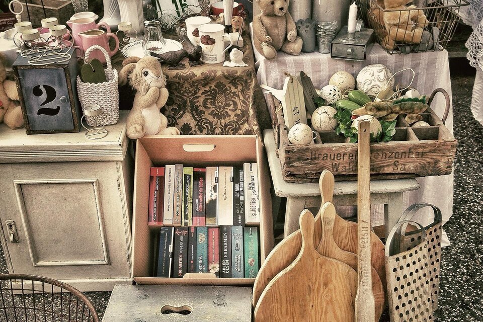 Ein Flohmarktstand mit verschiedenen Antiquitäten und Dekoartikeln. Es sind Bücher, Stofftiere und Geschirr zu sehen. | © Pixabay