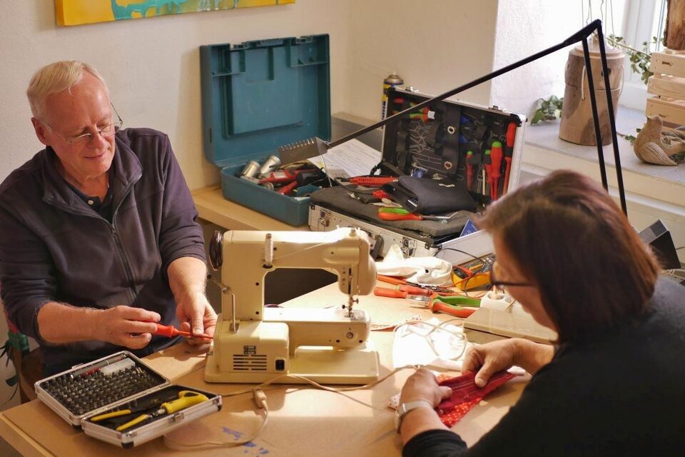 Zwei Personen arbeiten an einem Tisch mit einer Nähmaschine und verschiedenen Werkzeugen. Es herrscht eine kreative Atmosphäre, während sie gemeinsam an einem Projekt arbeiten. | © Arzberger