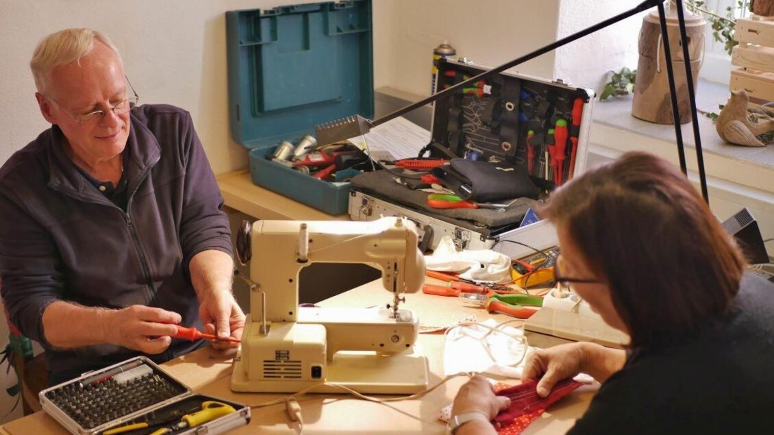 Zwei Personen arbeiten an einem Tisch mit einer Nähmaschine und verschiedenen Werkzeugen. Es herrscht eine kreative Atmosphäre, während sie gemeinsam an einem Projekt arbeiten. | © Arzberger