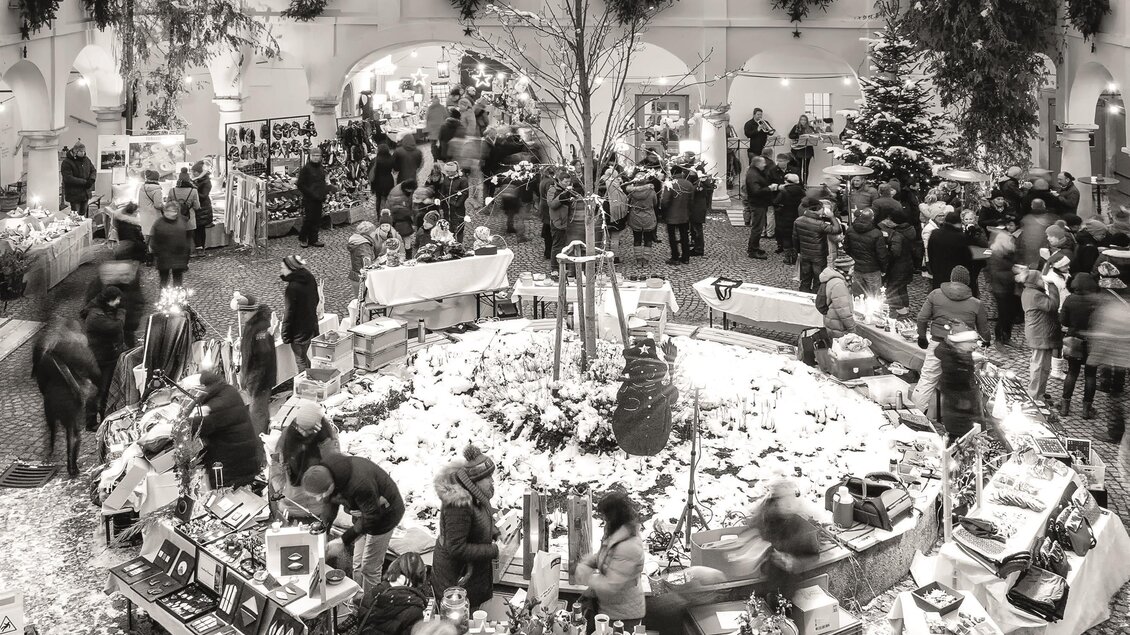 Ein gemütlicher Weihnachtsmarkt mit vielen Ständen und fröhlichen Menschen. Schneebedeckte Landschaften sorgen für eine festliche Atmosphäre. | © Retzhof_Niki Schreinlechner