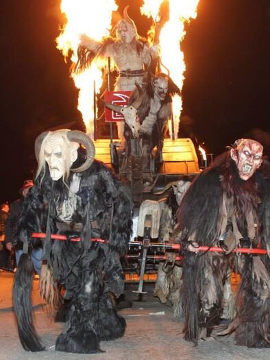A festive parade with grotesque masks and costumes. The scene is lively, with crowds of people and flaming fire in the background. | © Lembacher Eisteifln