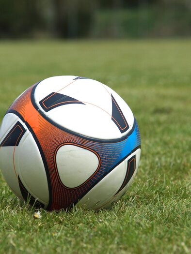 Ein Fußball liegt auf einem grünen Rasen. Der Ball hat ein modernes, buntes Design. | © Pixabay