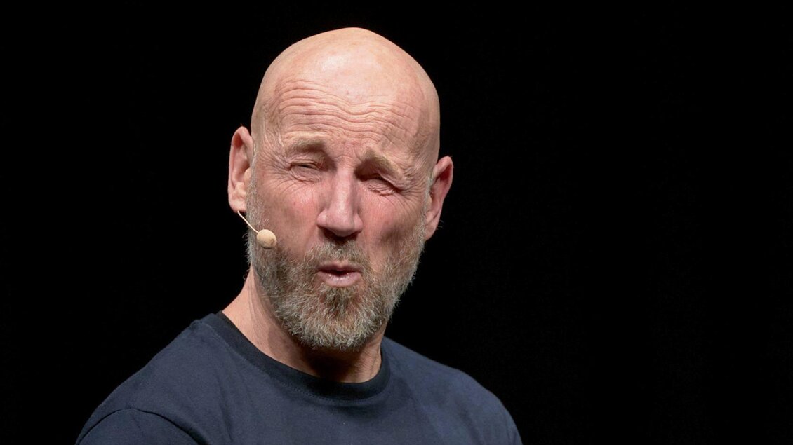 Ein Mann mit einer Glatze und einem Bart macht einen lustigen Gesichtsausdruck. Er trägt ein einfaches schwarzes T-Shirt und hat ein Mikrofon am Ohr. | © dueringer-regenerationsabend-3.0-bem-altaussee-foto-ernesto-gelles