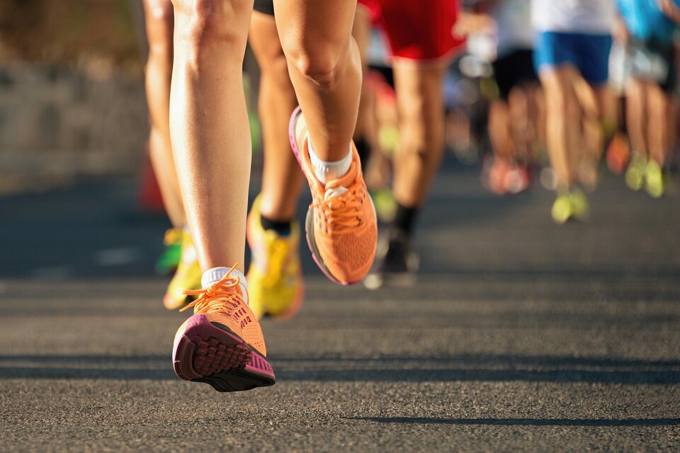 Läufer in bunten Schuhen bei einem Wettlauf auf der Straße. Im Hintergrund sind viele weitere Teilnehmer zu sehen. | © Adobe Stock
