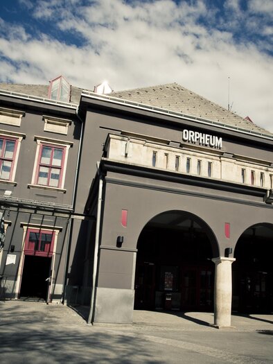 A historic building named "Orpheum". It has an elegant facade and a clear, blue sky in the background. | © Spielstätten - Lupi Spuma