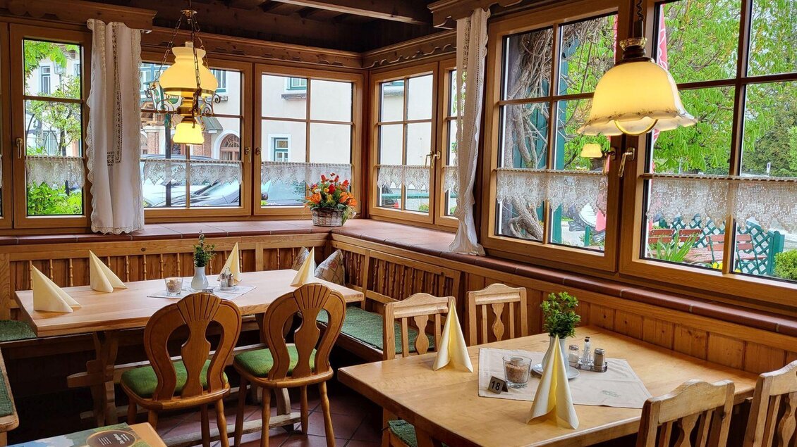 <p>Ein gemütlicher Wintergarten im Gasthof Berndl mit Holzmöbeln und großen Fenstern. Die Tische sind gedeckt und es gibt Pflanzen und frische Blumen auf den Fensterbänken.</p> | ©  Petra Kirchschlager